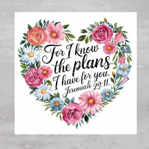 May include: A white background with a heart-shaped floral wreath. The wreath is made of pink, red, and blue flowers. The text "For I know the plans I have for you. Jeremiah 29:11." is written in black inside the wreath.