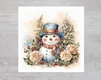 以下が含まれることがあります： 青い帽子と赤いマフラーをした雪だるまの水彩画。白いバラと緑の葉に囲まれている。