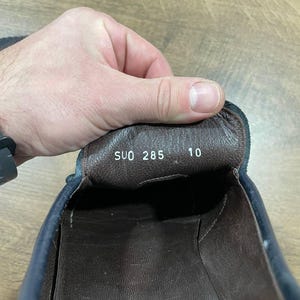 May include: Close-up of the interior of a navy blue leather shoe. The shoe's insole is brown with the text "SUO 285" and the number "10" printed on it. The words "MADE IN ITALY" are visible.