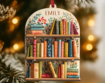 May include: Wooden bookshelf ornament with the name "EMILY" at the top. The ornament features a detailed bookshelf design with colorful books and floral accents. A red ribbon is attached for hanging.