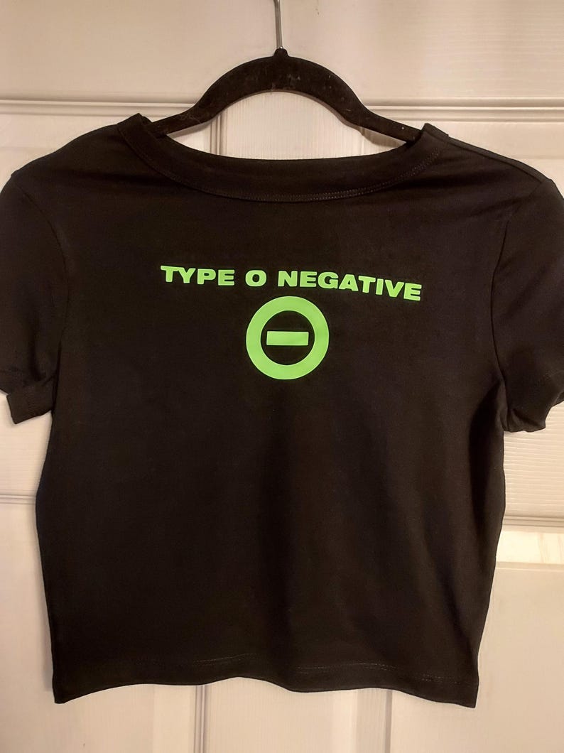 Puede incluir: Camiseta negra recortada con un gr&aacute;fico verde del logotipo de la banda Type O Negative, un c&iacute;rculo con una l&iacute;nea horizontal.