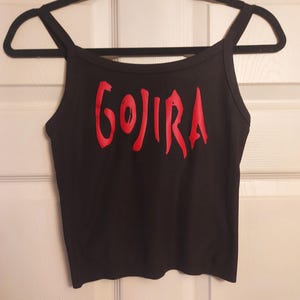 Puede incluir: Top negro de tirantes finos con la palabra "GOJIRA" impresa en rojo en la parte delantera.