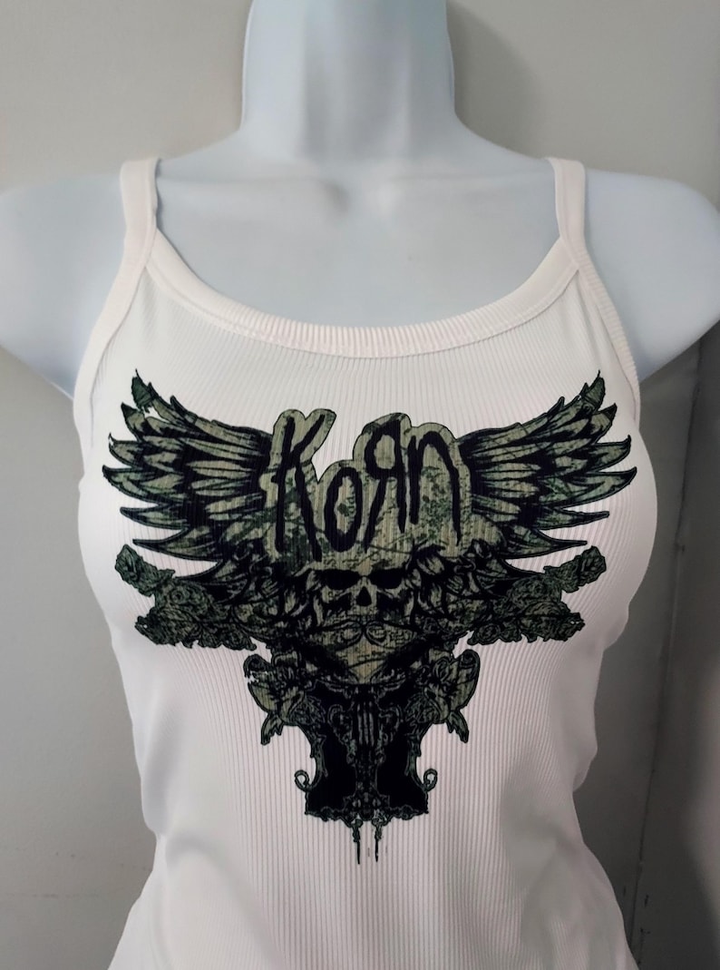 May include: White ribbed tank top with a black and green graphic print of a skull with wings and the word "Korn" above it.
