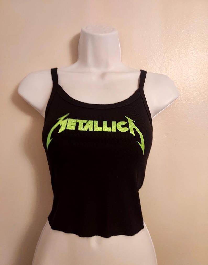 May include: Black tank top with a green "Metallica" logo.