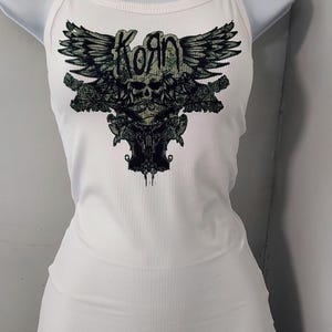 May include: White tank top with a black and green graphic of a skull with wings and the word "Korn" above it.