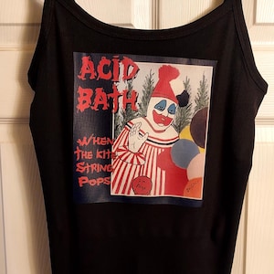 Op de afbeelding: Zwarte tanktop met een afbeelding van een clown en de tekst "ACID BATH" en "WHEN THE KITE STRING POPS". De clown heeft een rood-wit gestreept kostuum en een rode hoed. De tanktop heeft dunne bandjes.