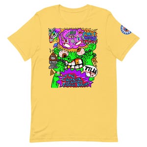 Puede incluir: Una camiseta amarilla con un gráfico colorido de un monstruo verde con un cerebro morado y el texto "The Creature with the Pinball Brain!". El diseño incluye un OVNI, un trofeo de caca y la palabra "TILL!"
