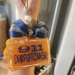 May include: Orange and white glitter 911 Dispatcher car air freshener with a blue and white ribbon.