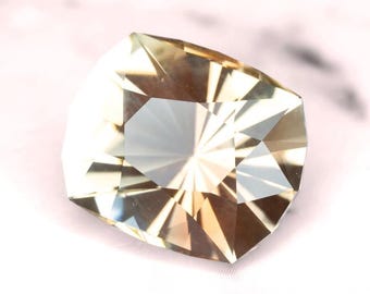 May include: A clear, faceted gemstone with a golden hue. The stone has a starburst pattern in the center.