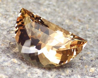 May include: A large, faceted, golden brown gemstone with a half-moon shape.