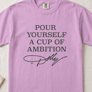 Lavender t-shirt with "Pour Yourself A Cup Of Ambition Dolly" text.