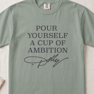 Light green t-shirt with "POUR YOURSELF A CUP OF AMBITION Dolly" text.