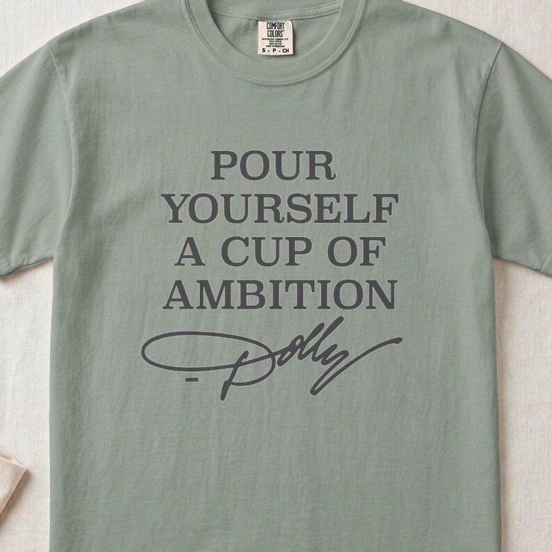 Light green t-shirt with "POUR YOURSELF A CUP OF AMBITION Dolly" text.