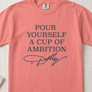 Coral t-shirt with "Pour Yourself A Cup Of Ambition Dolly" text.