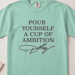 Mint green t-shirt with "POUR YOURSELF A CUP OF AMBITION Dolly" text.
