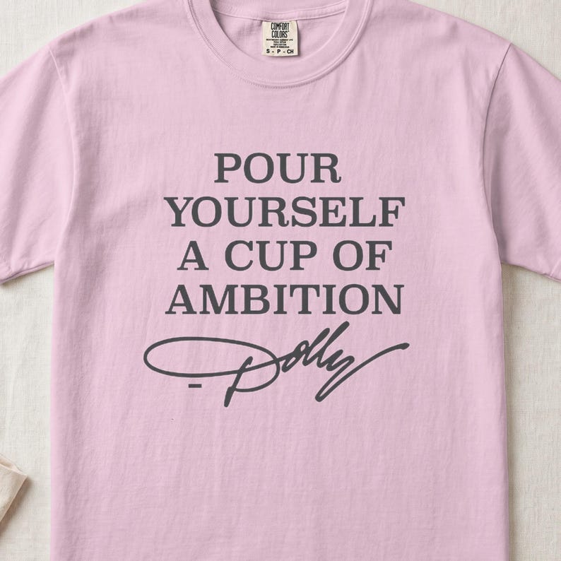 Pink Comfort Colors t-shirt with text "Pour Yourself a Cup of Ambition" and Dolly's signature.