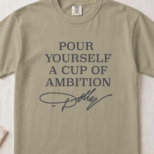 T-shirt with "Pour Yourself A Cup Of Ambition Dolly" text.