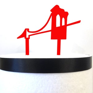 Puede incluir: Topper de pastel en silueta roja del Golden Gate Bridge. El topper est&aacute; hecho de acr&iacute;lico y es perfecto para un pastel con tem&aacute;tica de San Francisco.