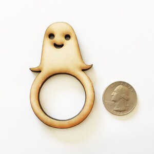 May include: Wooden ghost napkin ring with a smiling face. The ring is about the size of a US quarter.