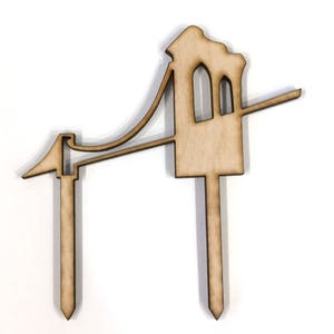 Puede incluir: Corte de madera de un puente con dos postes de apoyo. El puente es marr&oacute;n y tiene un dise&ntilde;o sencillo. El corte est&aacute; dise&ntilde;ado para ser utilizado como adorno de pastel.