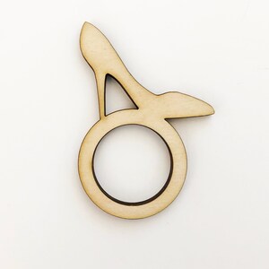 May include: A wooden napkin ring shaped like a high-heeled shoe. The ring is light brown and has a smooth finish.
