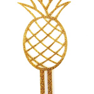 May include: Gold glitter pineapple cake topper with two long, thin stems.