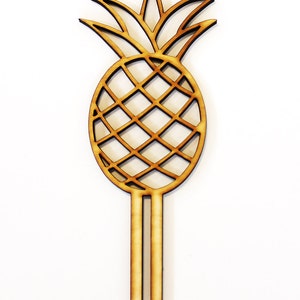 May include: Wooden pineapple cake topper with two prongs. The pineapple is a cutout design with a brown wood finish.