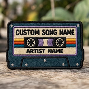 May include: Embroidered patch in the shape of a retro cassette tape. The patch features the text "CUSTOM SONG NAME" and "ARTIST NAME" in white, with a colorful striped design and a teal border. The cassette tape design is a nostalgic nod to the 80s and 90s.