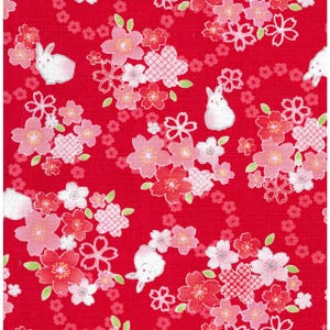 May include: Red fabric with a repeating pattern of white rabbits and pink and red cherry blossoms. The blossoms have white and pink petals, and the rabbits are outlined in white.