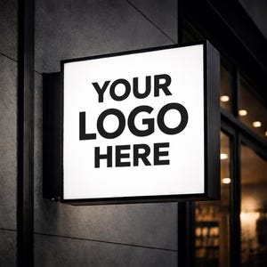 Może przedstawiać: Kwadratowy, podświetlany szyld z napisem "YOUR LOGO HERE" pogrubionymi, czarnymi literami. Szyld jest zamontowany na szarej, teksturowanej ścianie, z czarną ramą. Tło obejmuje witrynę sklepową.