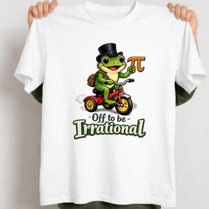 May include: White t-shirt with a cartoon frog on a red tricycle, wearing a top hat and holding a Pi symbol. The frog has a brown satchel. Text on the shirt reads "Off to be- Irrational".