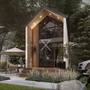 May include: A modern tiny house with a high-pitched roof, large windows, and wooden accents. The house has a small porch with outdoor furniture and a motorcycle parked nearby. The text "SAFE CAMP Design Studio" is visible.