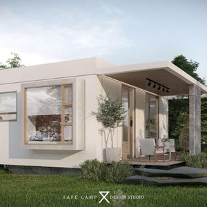 May include: A modern, white cabin with large windows and a covered porch. The cabin features a minimalist design with a flat roof and is surrounded by green grass and trees. The text "SAFE CAMP DESIGN STUDIO" is visible.