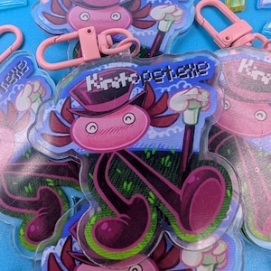 May include: A collection of clear acrylic keychains featuring a pink axolotl character wearing a top hat and holding a cane. The axolotl has a blushing face and the text "Kiritopet.exe" is above it. Each keychain has a pink clasp.