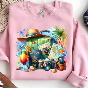 Puede incluir: Sudadera rosa claro con un dise&ntilde;o de acuarela de elementos de viaje. Presenta una maleta verde, pasaporte, c&aacute;maras, un mapa, un c&oacute;ctel, un sombrero de paja y conchas marinas. El dise&ntilde;o evoca un tema de vacaciones.
