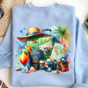 Puede incluir: Sudadera azul claro con un dise&ntilde;o tem&aacute;tico de viajes. El dise&ntilde;o incluye una maleta verde, un sombrero de paja, un pasaporte, un mapa, c&aacute;maras, un c&oacute;ctel y conchas marinas. La obra de arte es colorida y detallada, evocando vacaciones y aventura.