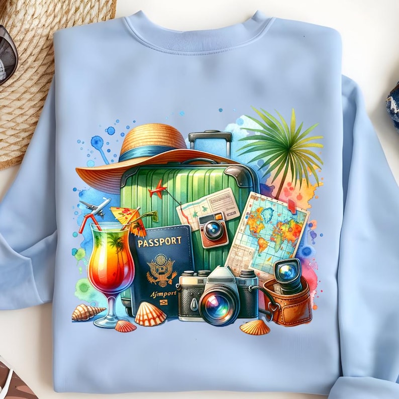 Puede incluir: Sudadera azul claro con un dise&ntilde;o tem&aacute;tico de viajes. El dise&ntilde;o incluye una maleta verde, un sombrero de paja, un pasaporte, un mapa, c&aacute;maras, un c&oacute;ctel y conchas marinas. La obra de arte es colorida y detallada, evocando vacaciones y aventura.