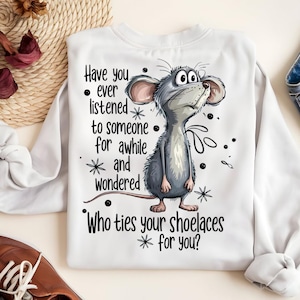 May include: White sweatshirt with a cartoon illustration of a gray mouse looking upwards. The text on the shirt reads: "Have you ever listened to someone for awhile and wondered, Who ties your shoelaces for you?"