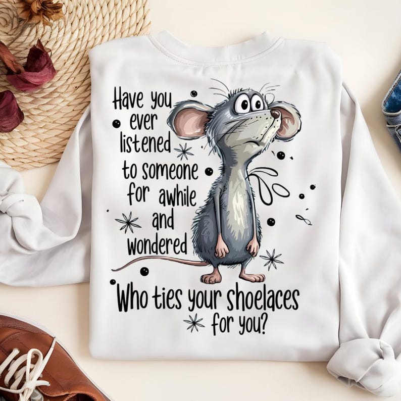 May include: White sweatshirt with a cartoon illustration of a gray mouse looking upwards. The text on the shirt reads: "Have you ever listened to someone for awhile and wondered, Who ties your shoelaces for you?"