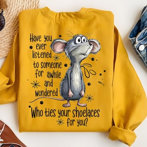 May include: Mustard yellow sweatshirt with a cartoon mouse illustration. The mouse is gray with large ears and is looking upwards. Text on the sweatshirt reads "Have you ever listened to someone for awhile and wondered Who ties your shoelaces for you?"