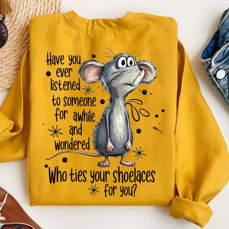 May include: Mustard yellow sweatshirt with a cartoon mouse illustration. The mouse is gray with large ears and is looking upwards. Text on the sweatshirt reads "Have you ever listened to someone for awhile and wondered Who ties your shoelaces for you?"