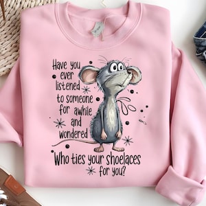 May include: Pink sweatshirt with a cartoon mouse illustration and the text "Have you ever listened to someone for awhile and wondered Who ties your shoelaces for you?" The mouse is gray with large ears and a curious expression.