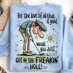 Puede incluir: Sudadera azul claro con un gr&aacute;fico humor&iacute;stico con tem&aacute;tica de golf. El dibujo animado representa a un golfista con el texto: "For the love of all that is good, would you JUST, GET IN THE FREAKIN' HOLE!" Tambi&eacute;n hay una pelota de golf y un sol.