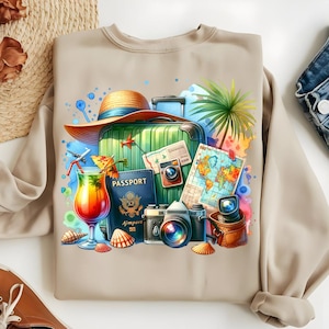 Puede incluir: Sudadera beige con un gr&aacute;fico colorido con tem&aacute;tica de viajes. El dise&ntilde;o incluye una maleta verde, un sombrero de paja, un pasaporte, c&aacute;maras, un c&oacute;ctel, un mapa y conchas marinas. El gr&aacute;fico tiene detalles de estilo acuarela y colores vibrantes.