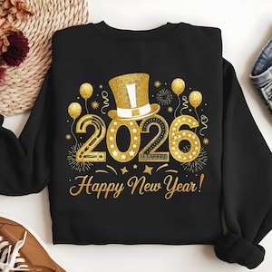 以下が含まれることがあります： 新年2026年のゴールドグリッターデザインが施された黒いスウェットシャツ。デザインには、シルクハット、風船、花火、そして「Happy New Year！」の文字が含まれています。