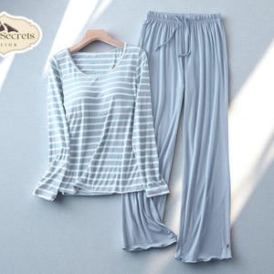 May include: A light blue pajama set. The long-sleeved top has a scoop neck and horizontal white stripes. The matching pants have a drawstring waist. The brand logo is in the upper left corner.