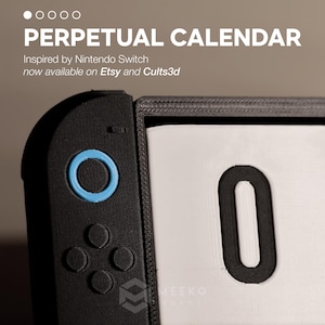 Op de afbeelding: Een zwart en blauw eeuwigdurende kalender geïnspireerd op de Nintendo Switch. De kalender heeft een groot wit display met het zwarte nummer "0". De tekst "PERPETUAL CALENDAR" staat bovenaan.