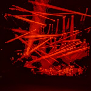 May include: A dark red abstract art piece with a black background. The art piece is made of many thin, red lines that are arranged in a chaotic pattern. The lines are all different lengths and thicknesses, and they create a sense of movement and energy.
