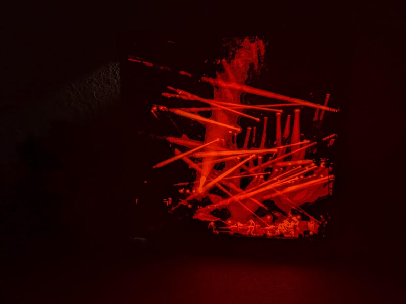 May include: A dark red abstract art piece with a black background. The art piece is made of many thin, red lines that are arranged in a chaotic pattern. The lines are all different lengths and thicknesses, and they create a sense of movement and energy.