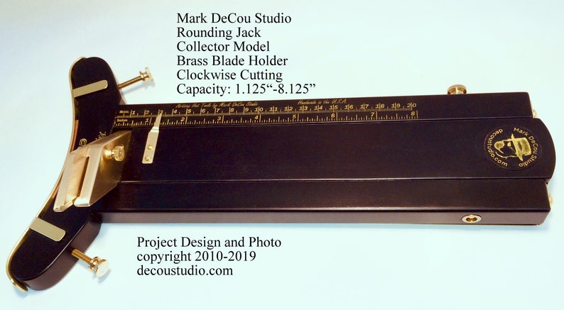 May include: A black wooden rounding jack with a brass blade holder and a ruler marked in inches. The jack is designed for clockwise cutting and has a capacity of 1.125 to 8.125 inches. The text "Mark DeCou Studio" is engraved on the jack.